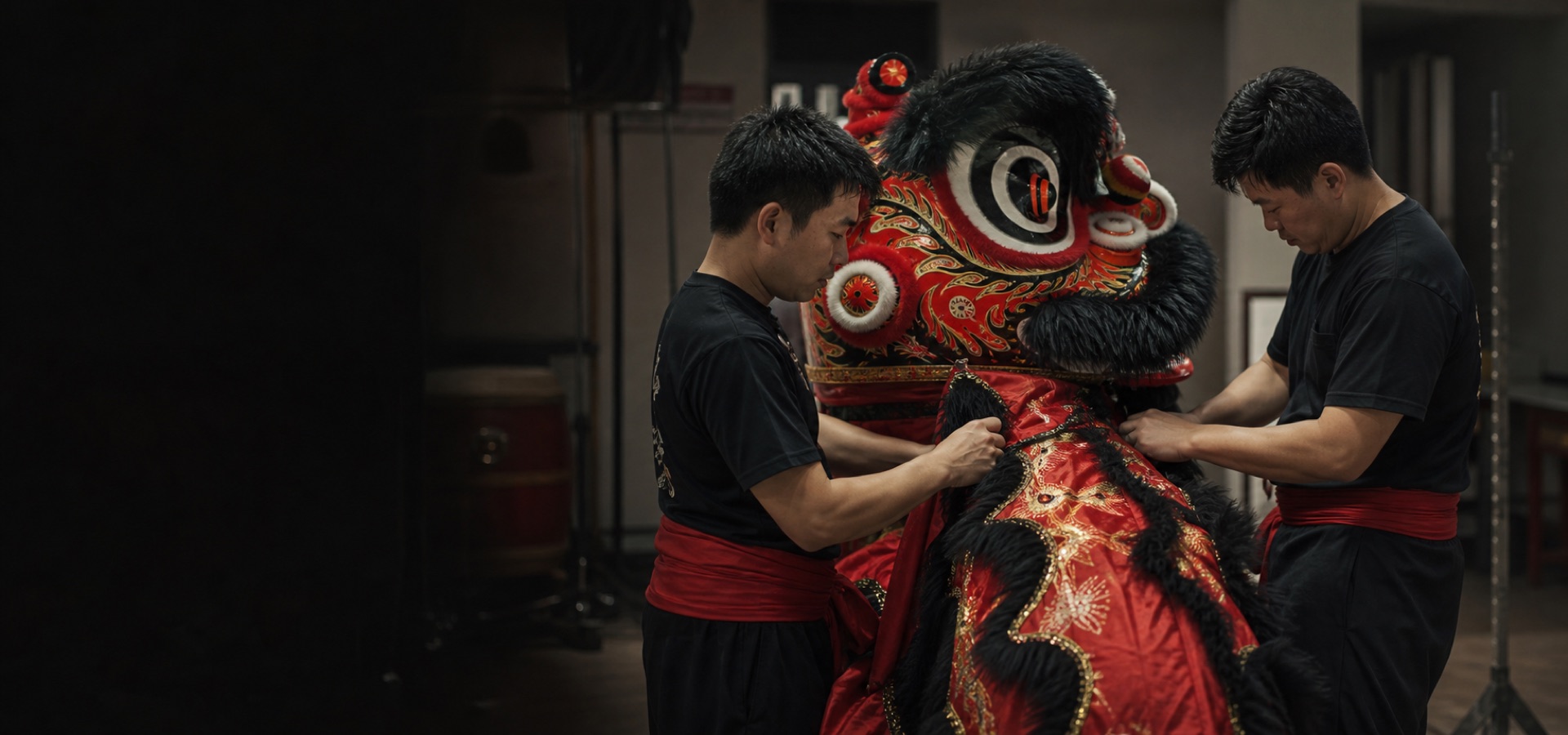 Two lion dance performers preparing a red and black lion head before a performance.