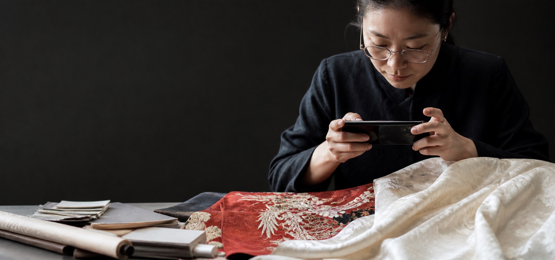 A researcher photographs the woven details of red and ivory hanfu textiles.