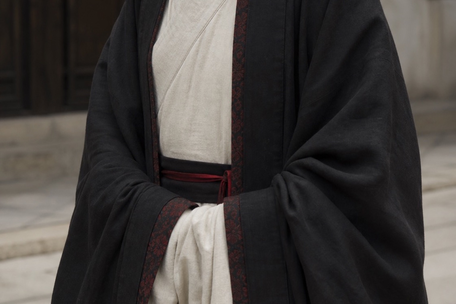 Layered black and ivory hanfu with restrained deep-red trim.