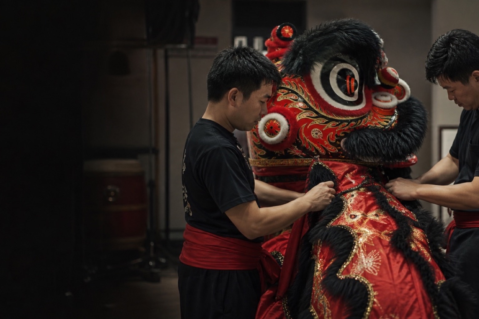 Two performers preparing the embroidered body of a black-and-red lion dance costume.